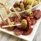Fuet fette di salame con olive verdi e peperoni; Con stuzzicadenti in legno — Foto stock