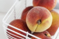 Fresh peaches in basket — Stock Photo