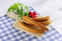Hot dogs et radis sur une planche à découper sur une serviette — Photo de stock
