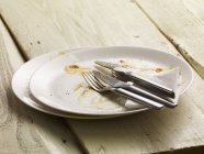 Closeup view of dirty plates with cutlery and a paper napkin — Stock Photo