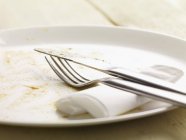 Closeup view of dirty plate with cutlery and paper napkin — Stock Photo