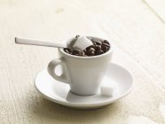 Vista close-up de uma xícara de grãos de café e cubos de açúcar — Fotografia de Stock
