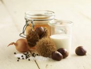 Ingredients for chestnut soup in jars over wooden surface — Stock Photo