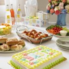 Vista elevada de palabra de bebé en la torta con diferentes platos y bebidas en la mesa - foto de stock