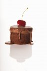 Closeup view of cake with chocolate sauce and cherry on white surface — Stock Photo