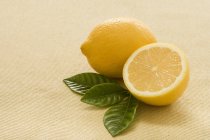 Frische Zitrone mit der Hälfte und Blättern — Stockfoto