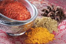 Closeup view of various spices in metal bowls and on red patterned cloth — Stock Photo