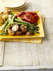 Grilled vegetables on yellow plates over wooden surface — Stock Photo