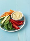 Crudite with Hummus  on blue plate over wooden surface — Stock Photo