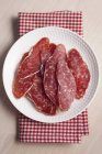 Slices of fuet salami in plate — Stock Photo