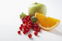 Rote Johannisbeeren mit Orangenkeil und Apfel — Stockfoto