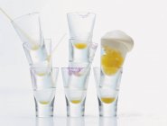Closeup view of orange shot with cream and piles of glasses — Stock Photo
