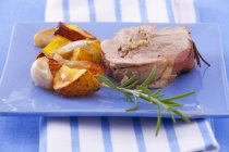 A slice of turkey roulade with rosemary and a side of vegetables on blue plate — Stock Photo