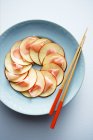 Верхний вид яблочного карпаччо с имбирем и палочками на тарелке — стоковое фото