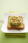 A slice of toast topped with asparagus tatar on white plate  over green towel — Stock Photo