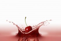 Cherry falling into red juice — Stock Photo