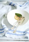 Closeup view of knife with fork, lemon and sage leaf on white plate — Stock Photo