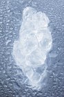 Close-up vista superior de um pedaço de gelo em uma superfície molhada — Fotografia de Stock