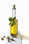 Un aceite de avellana en una botella y avellanas sobre fondo blanco - foto de stock