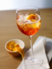 Vue rapprochée d'Aperol Spritz avec glaçons et écorces d'orange en verre tulipe — Photo de stock