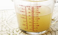 Closeup view of chicken broth in a measuring cup — Stock Photo