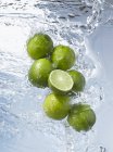 Limes falling into water — Stock Photo