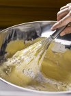 Closeup view of hand mixing flour to dough in metal bowl — Stock Photo