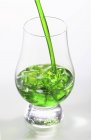 Vista de cerca del licor verde con hielo y paja en vidrio - foto de stock