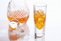 Primo piano vista di liquore arancione in un bicchiere e in una caraffa — Foto stock