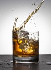 Cubos de hielo cayendo en whisky - foto de stock