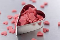 Vista de cerca del cortador de galletas en forma de corazón y corazones de azúcar - foto de stock