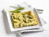 Slice of Asparagus Frittata on a White Plate over towel — Stock Photo