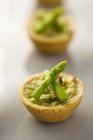 A mushroom tartlet with green asparagus on white blurred surface — Stock Photo