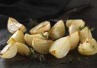 Cebollas cippolini asadas con tomillo en la superficie negra - foto de stock