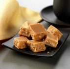 Closeup view of maple fudge pieces on black plate — Stock Photo