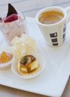 Крупный план кофе и выбор десертов на фарфоровой тарелке — стоковое фото