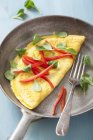 Closeup view of an omelette with pepper, basil and fork in pan — Stock Photo