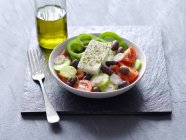 Греческий салат рядом с бутылкой — стоковое фото