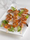 Closeup view of grilled shrimp skewers with lime and basil on a platter — Stock Photo
