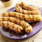 Closeup view of Churros with chocolate sauce on purple plate — Stock Photo