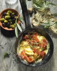 Huevos revueltos de tomate con cebolla, aceitunas negras y verdes, aceite de oliva, un manantial de olivo, ciabatta de oliva y lavanda - foto de stock