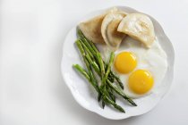 Fried eggs with pierogi and green asparagus — Stock Photo