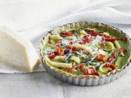 Courgette and pepper quiche in a dish  over wooden surface with towel — Stock Photo