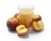 Glass of peach juice and fresh peaches — Stock Photo