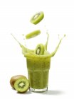 Kiwi slices falling into juice — Stock Photo