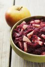 Apple-red cabbage and a fresh apple in green bowl on wooden surface — Stock Photo