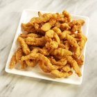 Closeup view of fried clam strips on white dish — Stock Photo