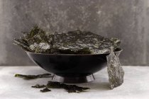 Closeup view of a black bowl of seaweed chips — Stock Photo