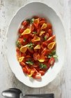 Салат из помидоров с лепестками роз на белой тарелке на деревянной поверхности — стоковое фото