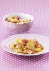 Kartoffelsalat mit roten Zwiebeln auf rosa Teller über rosa Oberfläche — Stockfoto